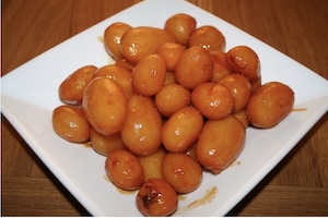 A bowl of small whole potatoes coated in light brown caramel